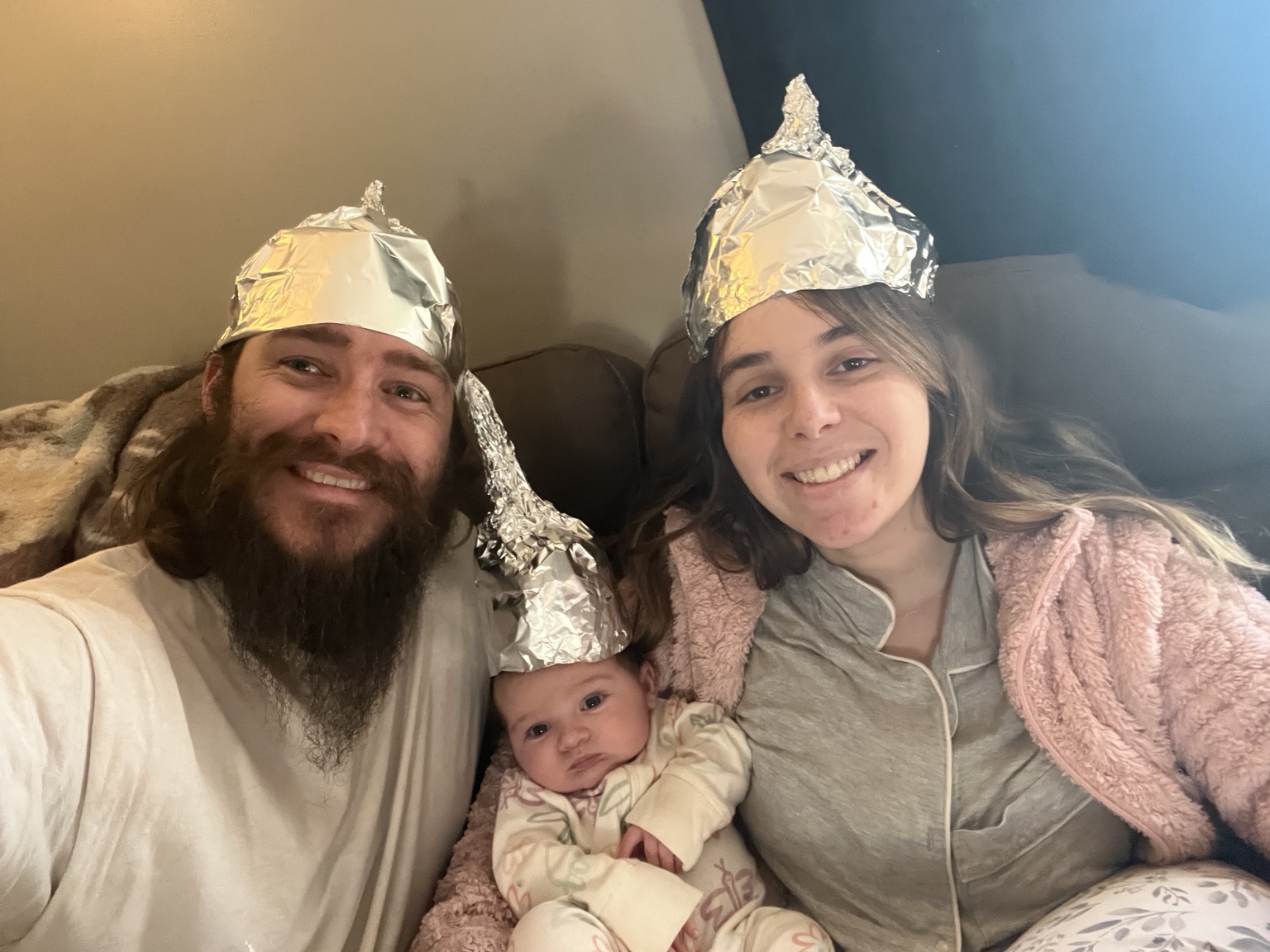 Skittles, his wife, and their daughter sharing a playful moment wearing foil hats