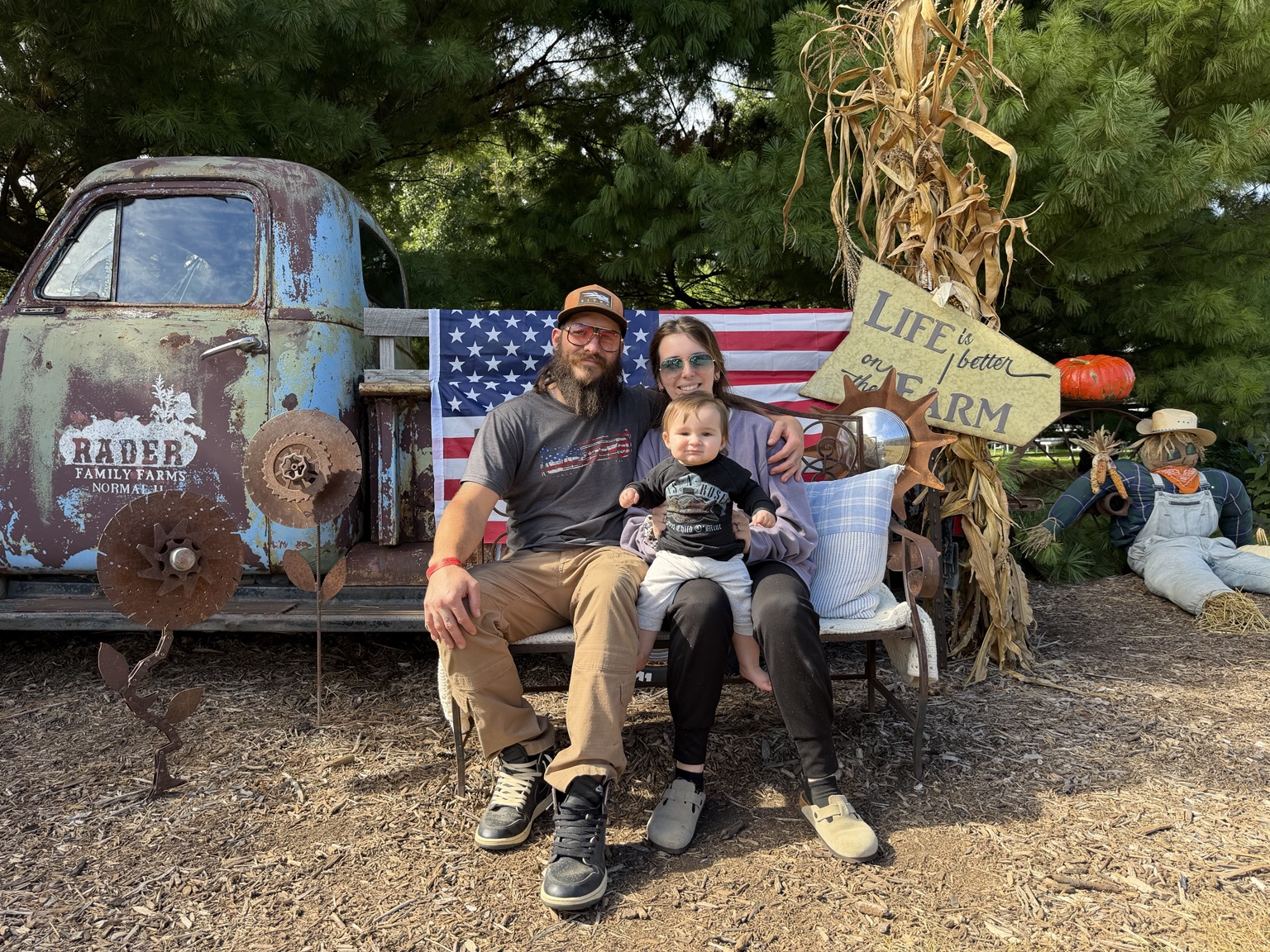 Skittles with his wife and daughter seated together by a vintage farm truck